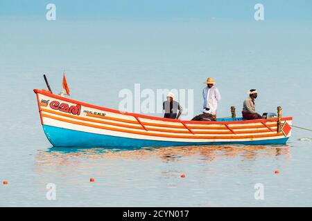Fischer in ihrem bunten Fischerboot auf dem Arabischen Ozean vor dem beliebten Marari Beach; Mararikulam, Alappuzha (Alleppey), Kerala, Indien Stockfoto