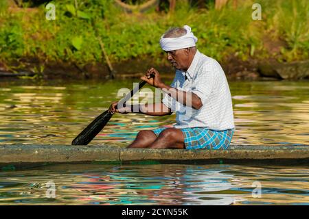 Old man Paddling Kanu in der Backwaters Region bekannt für Reisfelder & Hausboot Kreuzfahrten; Alappuzha (Alleppey), Kerala, Indien Stockfoto