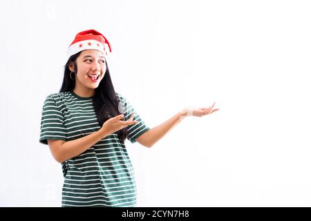 Porträt einer jungen asiatischen Frau trägt einen weihnachtsmann Hut und Das Tragen von legerer Kleidung stellt einen Kopierplatz auf der linken Seite dar Mit einem weißen isolierten Hintergrund Stockfoto