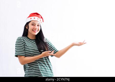 Porträt einer jungen asiatischen Frau trägt einen weihnachtsmann Hut und Das Tragen von legerer Kleidung stellt einen Kopierplatz auf der linken Seite dar Mit einem weißen isolierten Hintergrund Stockfoto