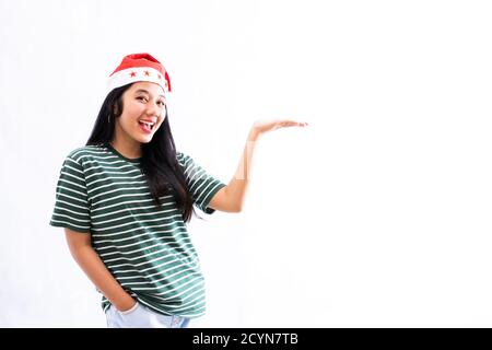 Porträt einer jungen asiatischen Frau trägt einen weihnachtsmann Hut und Das Tragen von legerer Kleidung stellt einen Kopierplatz auf der linken Seite dar Mit einem weißen isolierten Hintergrund Stockfoto