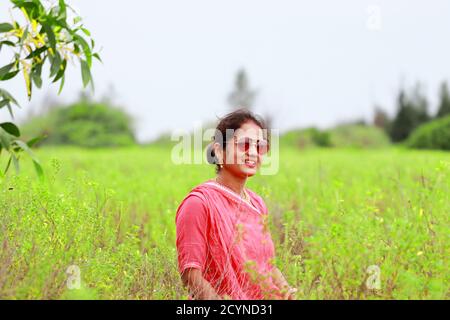 Indische Frau posiert in th Feld in Indian, trägt auf Augen stilvolle Sonnenglas, lachend an der Kamera Stockfoto