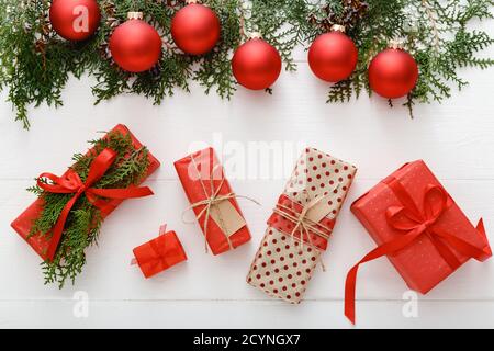 Weihnachten Komposition aus roten Weihnachten Geschenke, rot Christbaumkugel Dekorationen, Tannenbaum Äste auf weissem Holztisch Hintergrund. Weihnachten, Weihnachten, Winter Stockfoto