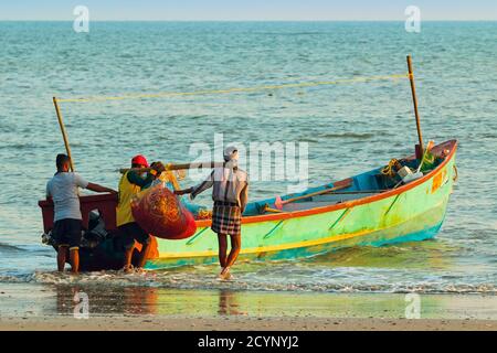 Fischer tragen Netze zum Boot am schönen Kizhunna Strand, südlich von Kannur an der Keralan Nth Küste; Kizhunna, Kannur, Kerala, Indien Stockfoto