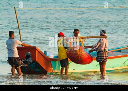 Fischer tragen Netze zum Boot am schönen Kizhunna Strand, südlich von Kannur an der Keralan Nth Küste; Kizhunna, Kannur, Kerala, Indien Stockfoto