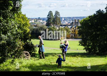 Mama Papa mit zwei kleinen Kleinkindern Kinder kleine Kinder, die zusammen in einem Park am Familientag in Ashton Court, Bristol, Avon, England, Großbritannien, spazieren gehen Stockfoto