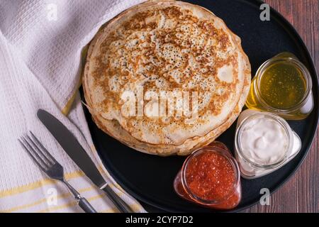 Pfannkuchen auf einem Teller mit rotem Kaviar, Honig und Sahne. Stockfoto