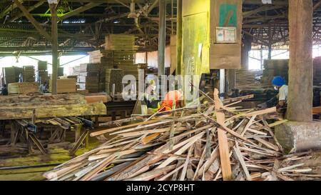 In einem Sägewerk im Industriegebiet Seguntor in Sandakan, Sabah, schneiden Arbeiter große Hölzer in Planken Stockfoto