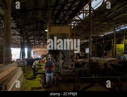 In einem Sägewerk im Industriegebiet Seguntor in Sandakan, Sabah, schneiden Arbeiter große Hölzer in Planken Stockfoto