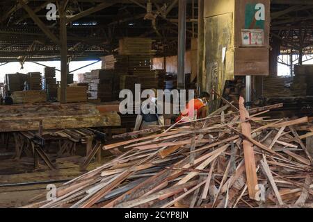 In einem Sägewerk im Industriegebiet Seguntor in Sandakan, Sabah, schneiden Arbeiter große Hölzer in Planken Stockfoto