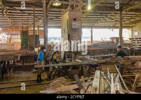 In einem Sägewerk im Industriegebiet Seguntor in Sandakan, Sabah, schneiden Arbeiter große Hölzer in Planken Stockfoto