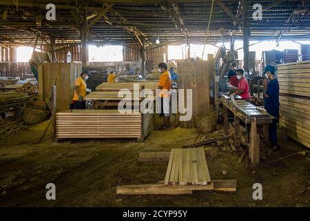 In einem Sägewerk im Industriegebiet Seguntor in Sandakan, Sabah, schneiden Arbeiter große Hölzer in Planken Stockfoto