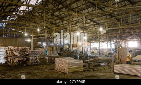 In einem Sägewerk im Industriegebiet Seguntor in Sandakan, Sabah, schneiden Arbeiter große Hölzer in Planken Stockfoto