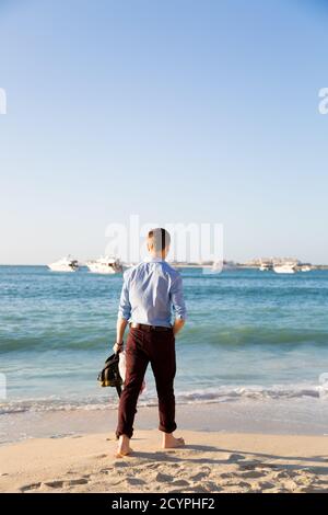 Ein gekleideter Mann geht nach der Arbeit am Meer entlang. Stockfoto