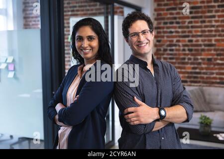 Porträt einer Frau mit gemischter Rasse und eines kaukasischen Mannes, der in einem legeren Büro arbeitet, lächelt und die Kamera anschaut. Kreative Business-Profis arbeiten in einem Stockfoto