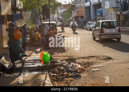 TAMILNADU, INDIEN - 09. FEBRUAR 2016: Eine indische Frau sammelt und trägt Wasser in Plastiktöpfen in einem Slum am Stadtrand von Coimbatore. Stockfoto