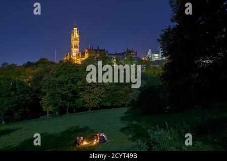 Studenten genießen einen Drink bei Kerzenschein bei Vollmond im Kelvingrove Park mit der Glasgow University in der Ferne. Stockfoto