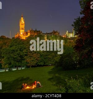 Studenten genießen einen Drink bei Kerzenschein bei Vollmond im Kelvingrove Park mit der Glasgow University in der Ferne. Stockfoto