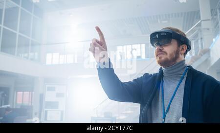 Automobilingenieur mit Augmented Reality Headset und berührende Gesten von virtuellen Objekten in der Luft. In Innovation High Tech Laboratory Stockfoto