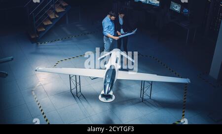 Treffen der Luft- und Raumfahrtingenieure arbeiten an unbemannten Luftfahrzeug Drohne Prototyp. Luftfahrtexperten diskutieren. Industrieanlage mit Flugzeugen Stockfoto