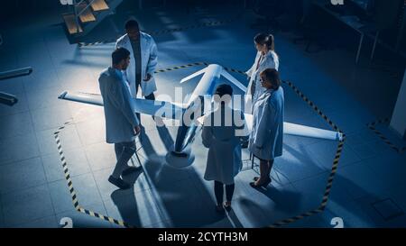 Treffen der Luft- und Raumfahrtingenieure arbeiten an unbemannten Luftfahrzeug Drohne Prototyp. Luftfahrtwissenschaftler in White Coats sprechen. Industrielles Labor mit Stockfoto