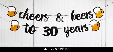 Ein 30. Geburtstag Party Banner liest jubeln und Biere zu 30 Jahren woth Bierkrüge auf beiden Enden Stockfoto