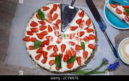 Appetitlich hausgemachter Käsekuchen mit Bio-Erdbeeren, Tasse Kaffee und Messer, Layout Stockfoto