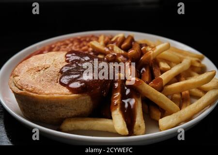 Steak und Kidney Pie, Chips, Bohnen und Soße Stockfoto