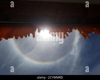 Die Sonnenscheinwolken oder Halos um die Sonne herum werden von hohen, dünnen Zirruswolken, winzigen Eiskristallen auf der Erde verursacht Stockfoto