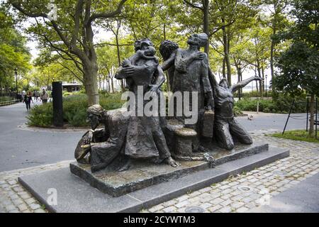 Battery Park, NYC: Bildhauer Luis Sanguino (geb. 1934) feiert die Vielfalt von New York City und den Kampf der Immigranten in dieser heroisch-großen bronzenen Figurengruppe "die Immigranten". Die Skulptur zeigt Figuren verschiedener Ethnien und Epochen, darunter einen osteuropäischen Juden, einen befreiten afrikanischen Sklaven, einen Priester und einen Arbeiter. Stockfoto