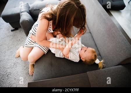 Mutter und Tochter umarmen sich in ihrem Haus. Eine glückliche Familie. Eine Mutter, die ein Kind aufziehen soll. Stockfoto