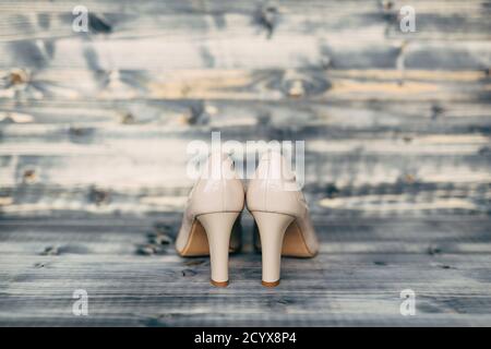 Beigefarbene Schuhe mit hohen Absätzen auf grauer Holzstruktur. Stockfoto