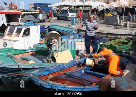 Fischer putzt die Decks seines Bootes und plaudert mit ihm Fischer Freund im Hafen in Trapani Altstadt Sizilien Stockfoto