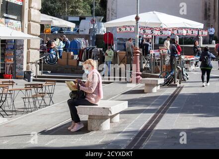 ROM, ITALIEN - OKTOBER 01 2020: Fußgänger, mit Schutzmaske, sitzt auf der Bank in Rom, Italien. Stockfoto
