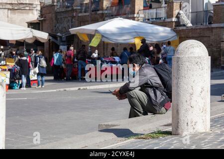 ROM, ITALIEN - OKTOBER 01 2020: Fußgänger, mit Schutzmaske, sitzt auf der Bank in Rom, Italien. Stockfoto