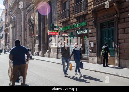 ROM, ITALIEN - OKTOBER 01 2020: Fußgänger, die eine Schutzmaske tragen, tragen eine Einkaufstasche in Romes Via del Corso, Italien. Stockfoto