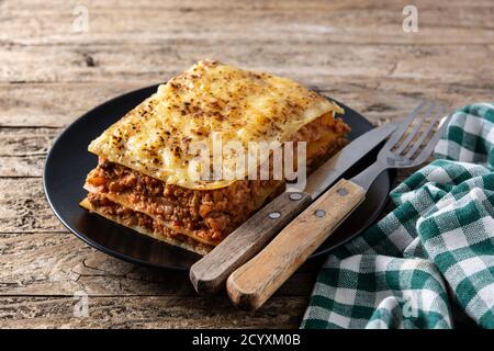 Stück Lasagne auf schwarzem Teller auf rustikalem Holz Tabelle Stockfoto
