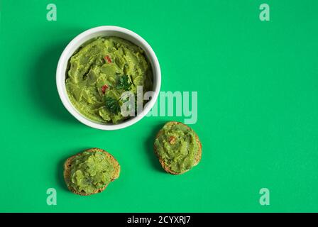 Eine weiße Schale und Crostini oder Bruschetta mit traditionellen mexikanischen Vorspeise Guacamole isoliert auf dem grünen Hintergrund Stockfoto