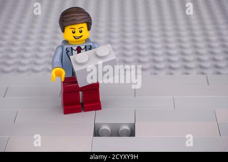 Tambow, Russische Föderation - 07. Juni 2020 Lego Geschäftsmann mit grauen Ziegel bereit, ein Loch zu füllen Stockfoto