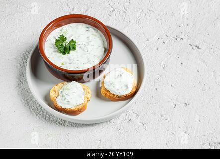 Eine Schüssel und Crostini oder Bruschetta mit traditioneller griechischer Tzatziki-Sauce auf dem grauen Teller. Vegetarische Vorspeise Stockfoto