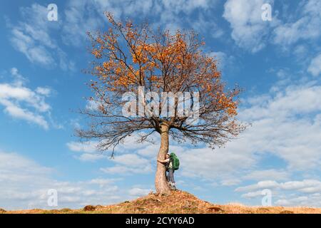 Tourist unter majestätischen Orangenbaum im Herbst Bergtal. Dramatische farbenfrohe Herbstszene mit blau bewölktem Himmel. Landschaftsfotografie Stockfoto