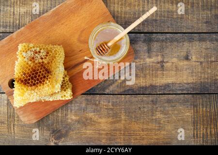 Honig in einem Glas und Wabe auf einem alten hölzernen Hintergrund. Draufsicht. Stockfoto