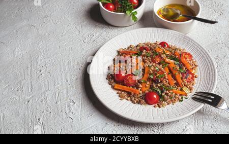 Gesunder vegetarischer Salat mit Buchweizen und Gemüse auf Weiß Platte auf grauem Hintergrund mit Kopierplatz Stockfoto