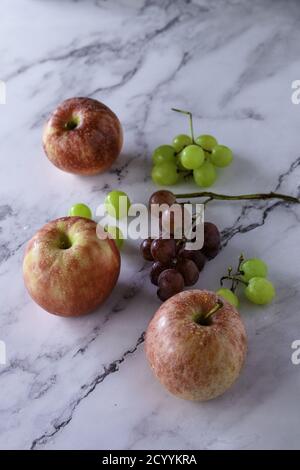 High-Angle Schuss von roten Äpfeln und Trauben isoliert auf einem Marmoroberfläche Stockfoto