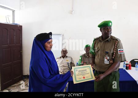 SSP. Francis Ndiema, Koordinator für Ausbildung und Planung der AMISOM-Polizei, überreicht eine Bescheinigung an eine Polizistin während der Abschlussveranstaltung eines von den Polizeikomponenten der Mission der Afrikanischen Union in Somalia (AMISOM) organisierten Workshops über Gemeinschaftspolizei und -Radikalisierung, Am 27. Juli 2019 in der General Kahiye Police Training Academy in Mogadischu, Somalia. Stockfoto