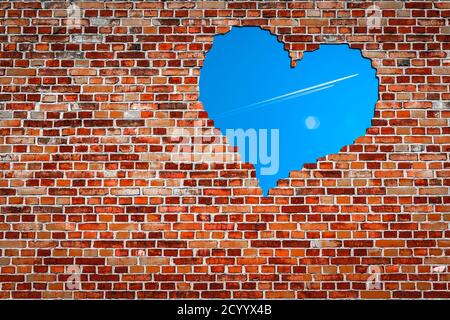 Rote Ziegelwand mit einem herzförmigen Loch, das Blau zeigt Himmel Stockfoto