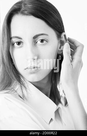 Ernst junge Frau in weißer Bluse Blick auf Kamera auf weißem Hintergrund, monochrom Stockfoto