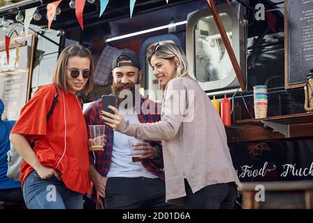 Eine Gruppe von Freunden trinkt Bier vor dem Food Truck Stockfoto