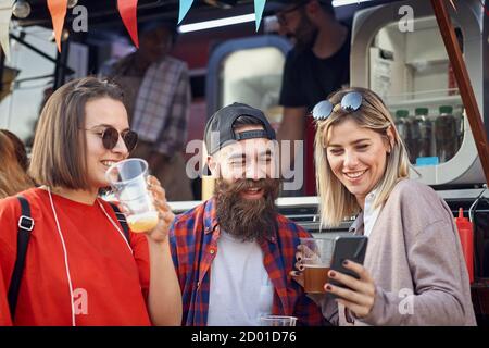 Eine Gruppe von Freunden trinkt Bier vor dem Food Truck Stockfoto