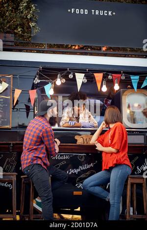 Hipster-Paar bei der Bestellung von Foodtruck auf der Straße; Urban Lifestyle-Konzept Stockfoto